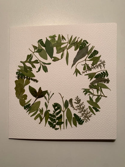 A circle of different green pressed leaves. All leaves have the same direction, upwards.