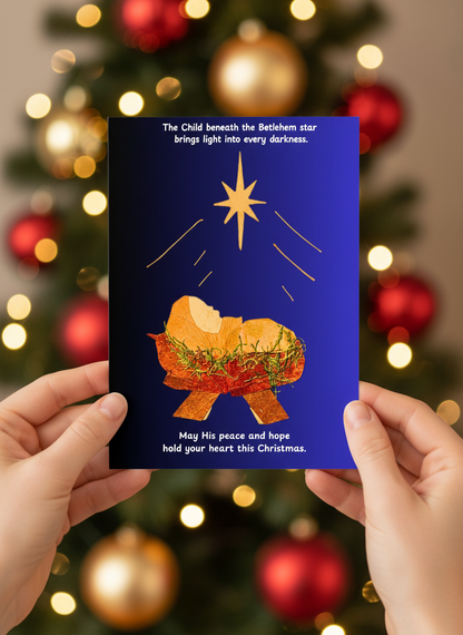 Womans; hands holding a christmas card  with christmas tree at the background. Design of the card is baby Jesus in a cradle under Betlehem star, made with pressed leaves and moss.