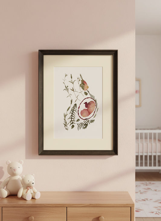 Framed artwork with a baby girl in a womb design.